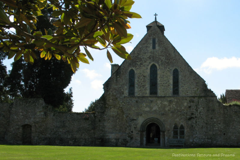 Stone church, once part of a Cistercian Abbey, with cross on top and three long narrow arched windows on upper story
