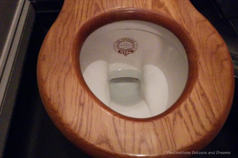Wooden toilet seat and porcelain bowl with Thomas Crapper emblazoned on bowl