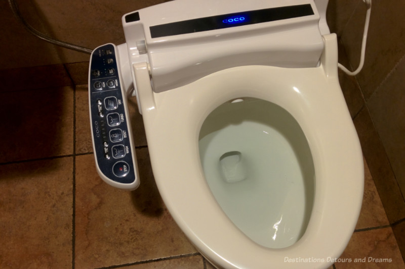 Bidet seat on a toilet with electronic controls on the side
