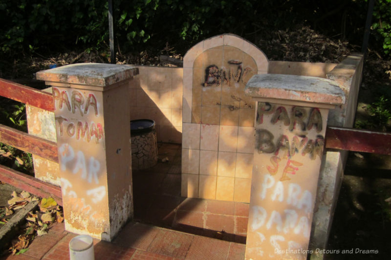 Rustic tiled non-very-private public toilet facilities walled only to about waist-high with pail inside to use