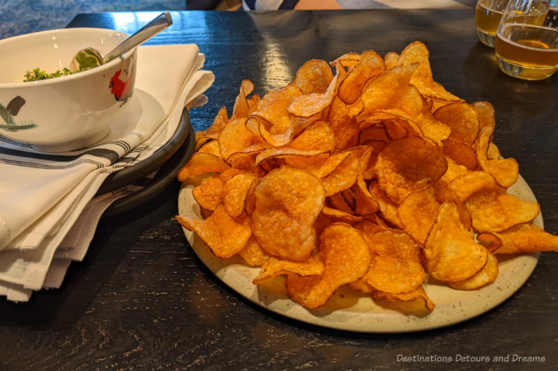 A plate of home made potato chips with a bowl of dip