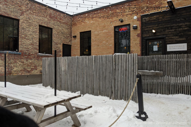 Brick building with snow packed ramp entrance bordered by wooden slat fencing