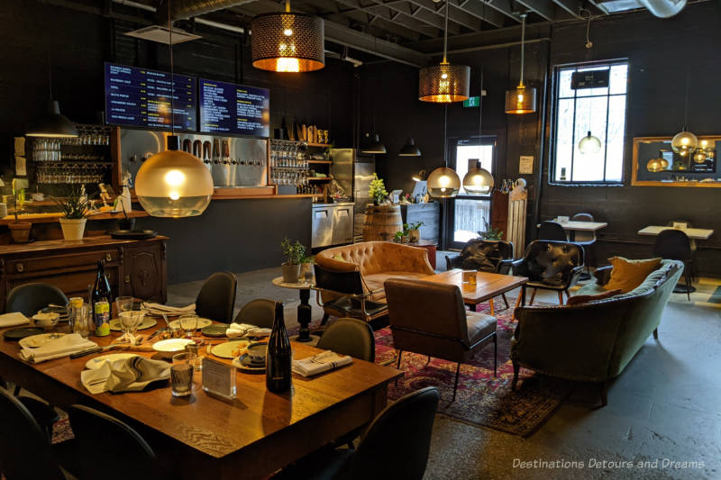  Casual, open living-room style concept with couches, low tables, and a barless bar / tap wall in a taproom