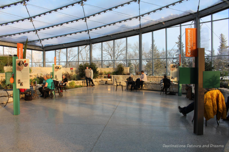 Open area in indoor Mediterranean garden with a few tables and seating along the brick edges of garden terraces