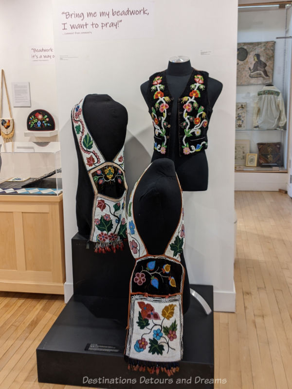 Indigenous embroidered vest and bandolier bags on display in a museum exhibit