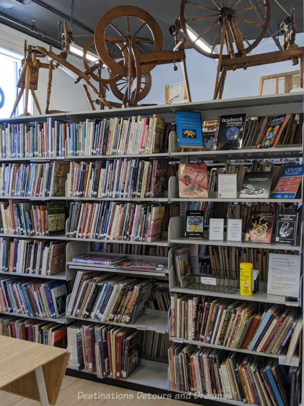 Library shelf of books with looms sitting atop shelf