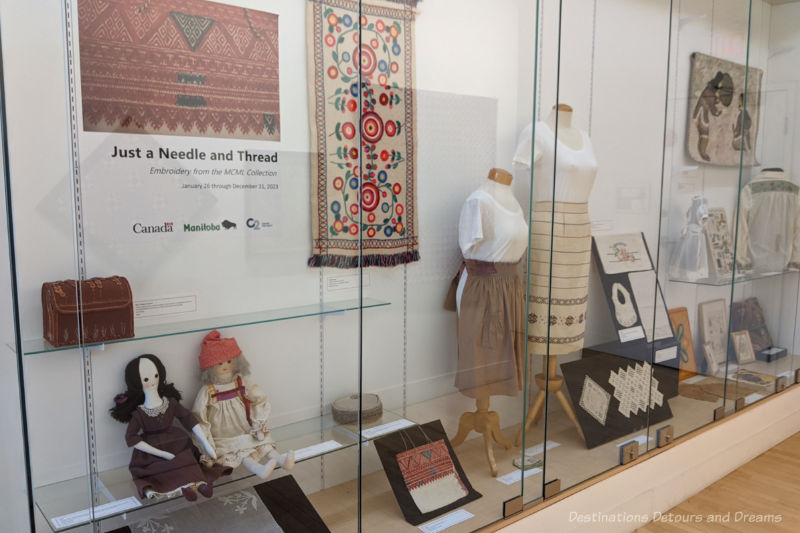 Collection of needlecraft on display behind a floor-to-ceiling glass wall