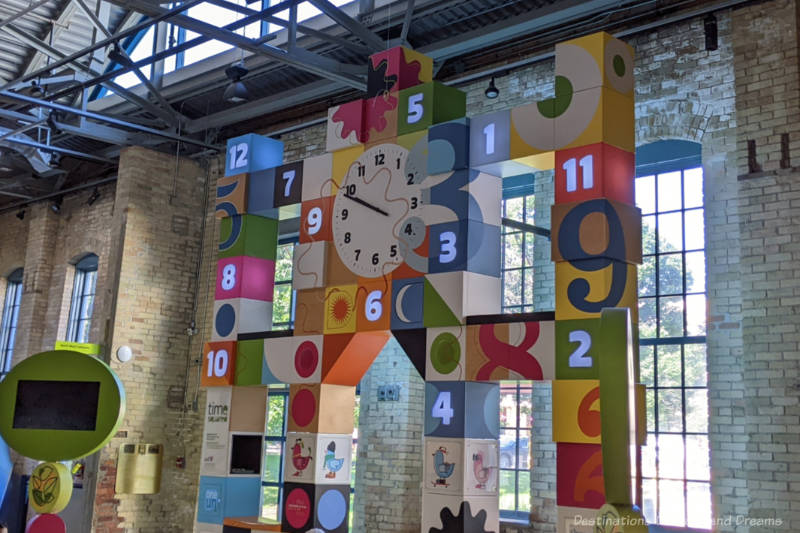 Colourful numbered blocks in a tower around a clock make up a time display at a children's museum
