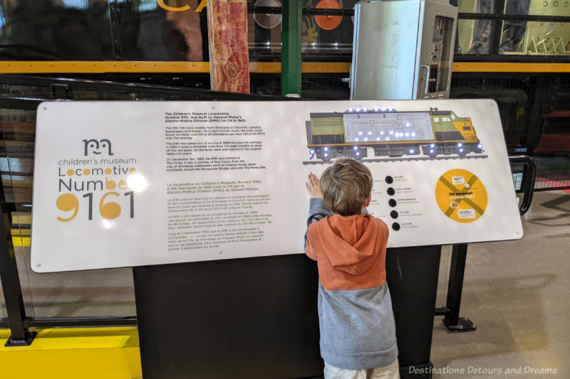 Children reading placard at a children's museum containing information about the parts of a locomotive