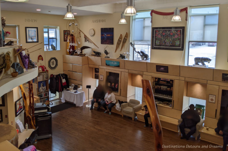 View of a large room with Indigenous art on display from a mezzanine level