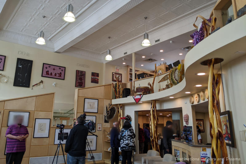 Indigenous centre space with high ceiling, curved wall under mezzanine level, and artwork on display