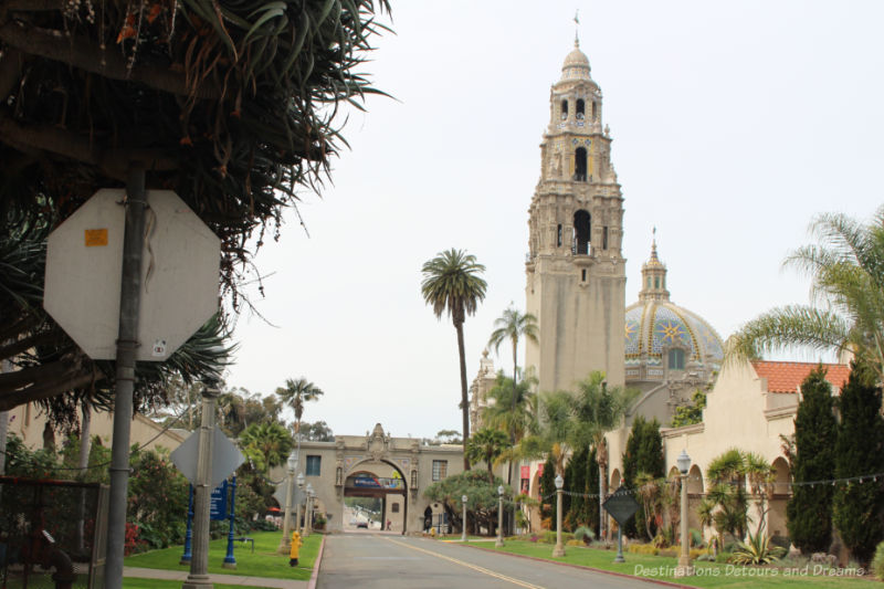 Bridge, street, a building with an ornate tower, and a building with a dome, all inside Balboa Park in San Diego