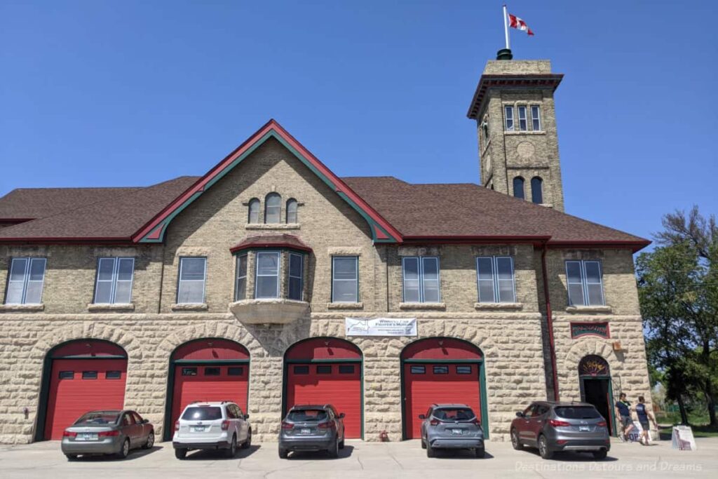 Brick front of an early 1900s fire station with four red garage doors