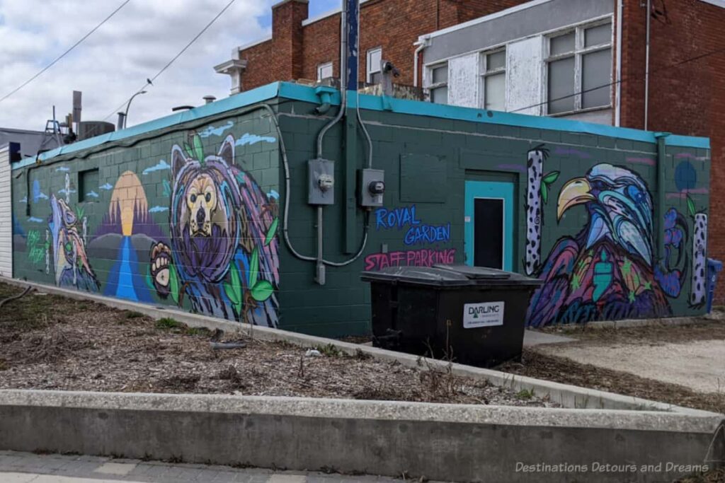 Mural of animals and nature scene on the back and side of a one-story building