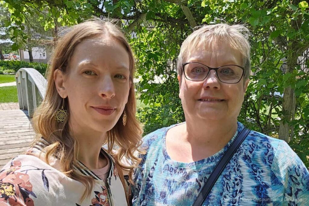 Mother and adult daughter in front of trees and wooden bridge