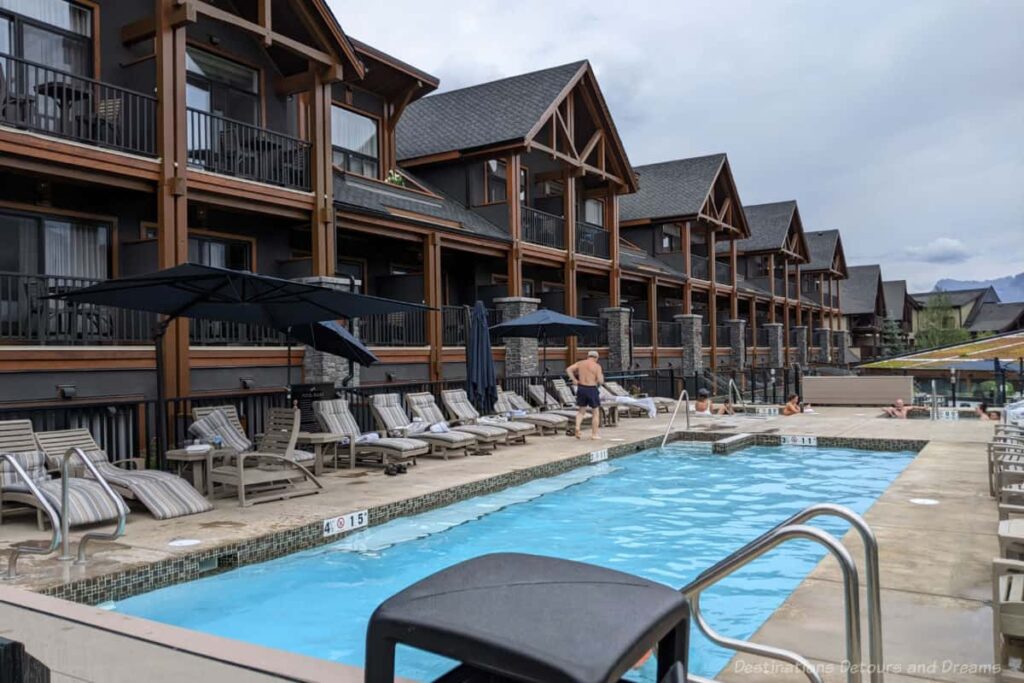 Outdoor hotel pool and hot tub area with two levels of chalet rooms with balconies along one side