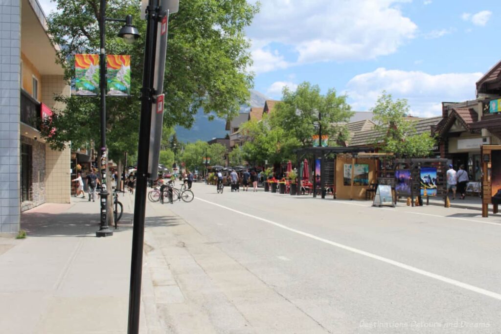 Pedestrian downtown main street of Canmore lined with shops, patios and mountain views