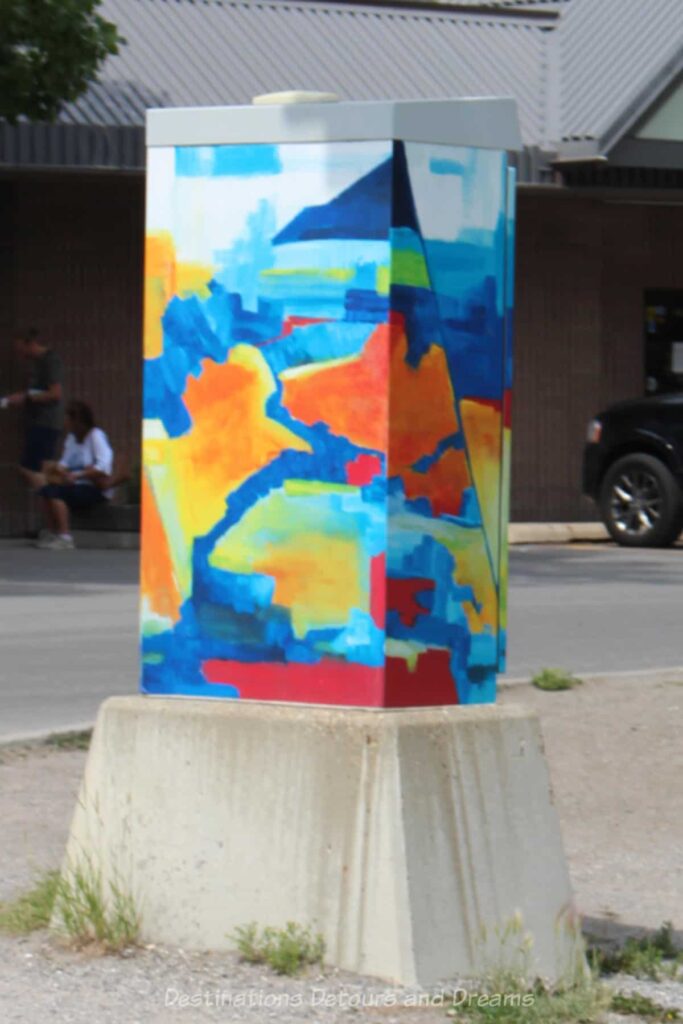 A utility box in Canmore painted in a design of bright red, yellow, and blue colours