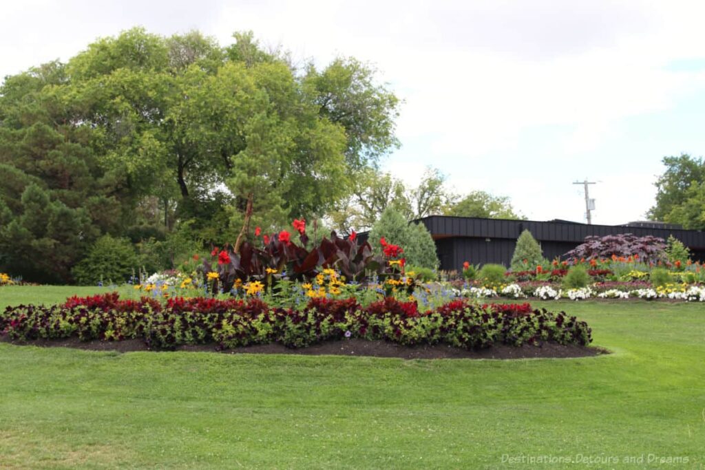 Kildonan Park circular flower bed featuring tap red canna lilies in the centre with yellow flowers around that and deep red flowers on the border 