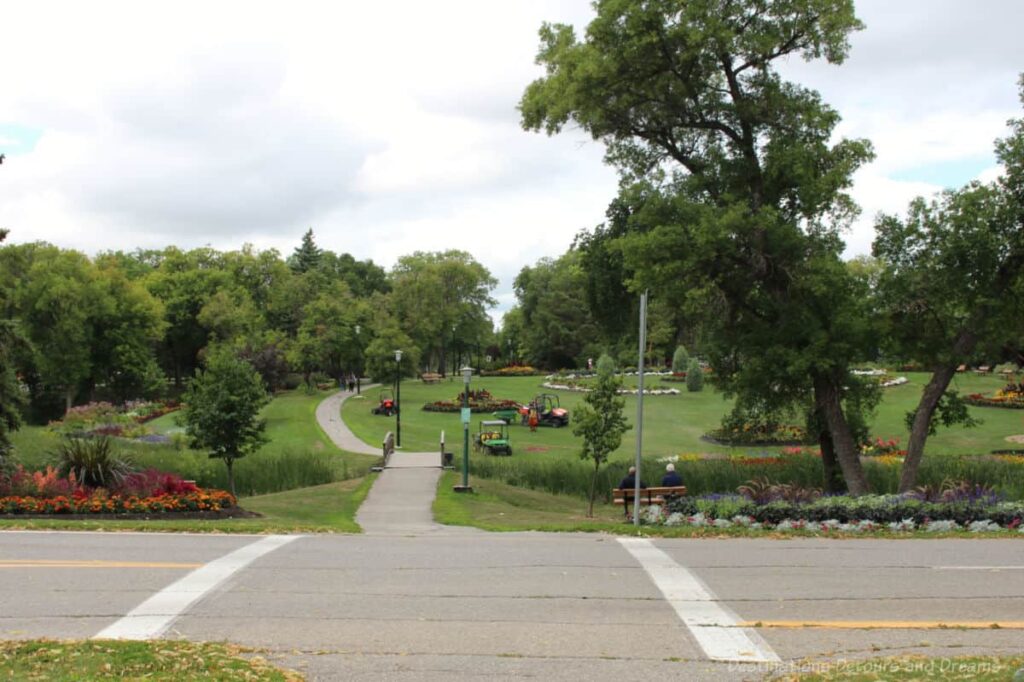 Path leading to green space containing several formal flower beds