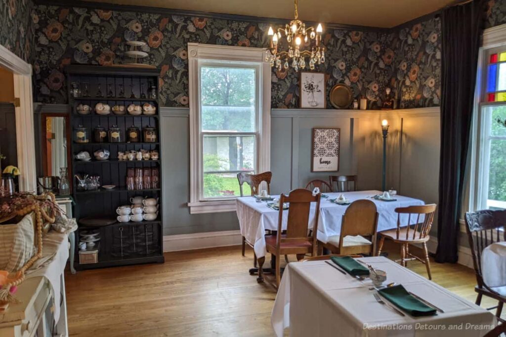 Restaurant dining area in the room of an old house with tall wainscotting on the walls and floral wallpaper above that