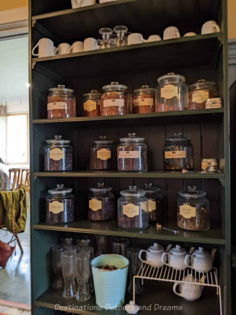 Tall shelf containing cups and jars of loose leaf tea