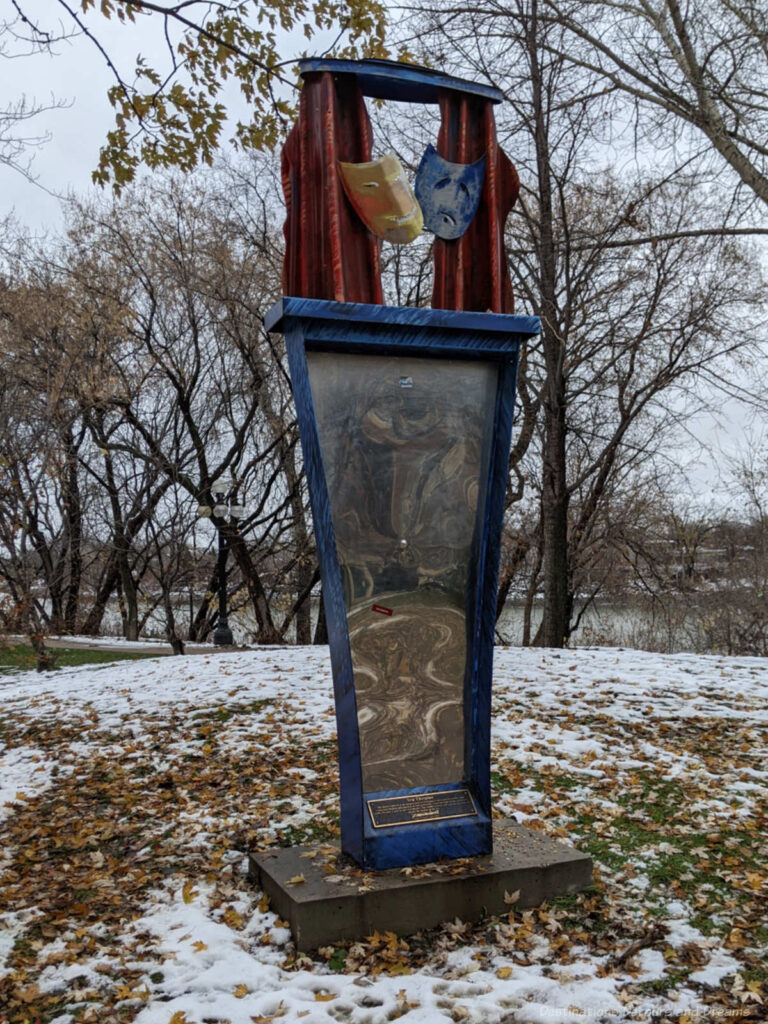 Piece of public art contain theatre masks and stylized drawing entitled You Thespian