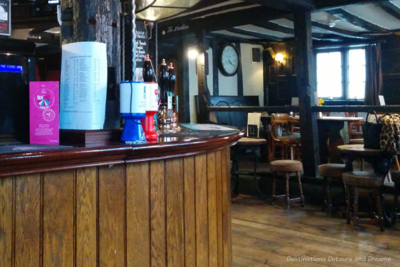 Things to know about English pubs - interior of pub with wood beams, tables, and wood bar