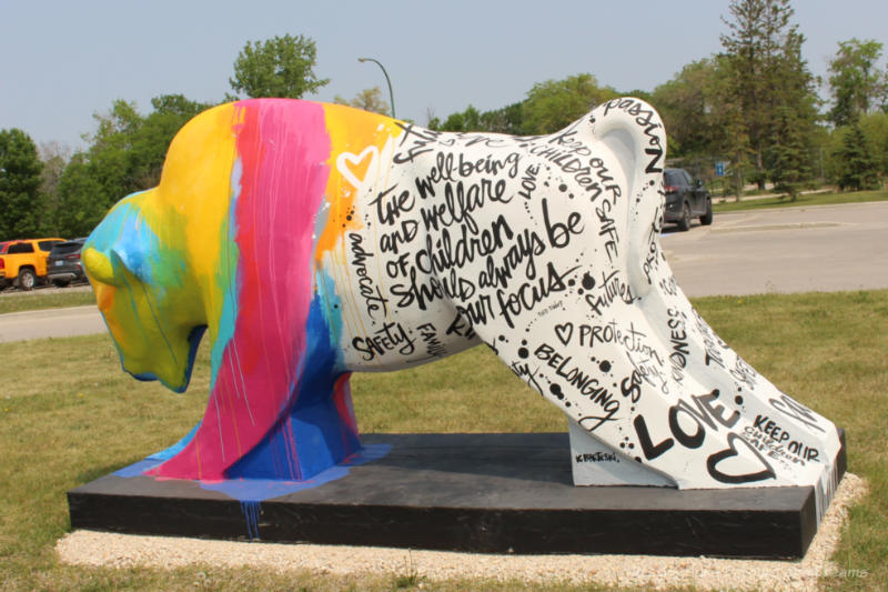 Bison on the Boulevard love + words bison A concrete bison with its front half painted in strips of bright colour and its back half covered with hand-written phrases about love and the well-being of children