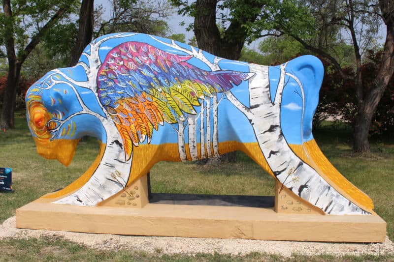 Bison on the Boulevard Soaring Resistance Concrete bison with body painted blue, legs and mouth orange, and with images of coloured wings and intertwining birches painted on it