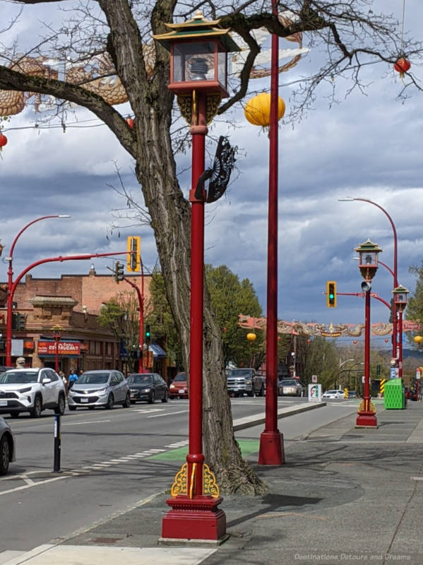 Row or red streetlamps at the edge of Chinatown with a sculpture of a hand holding a fan on the foremost one