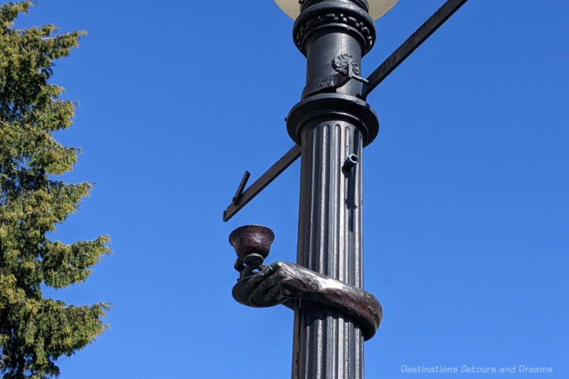 Street lamp post with a bronze sculpture of hands holding a tea cup wrapped around it