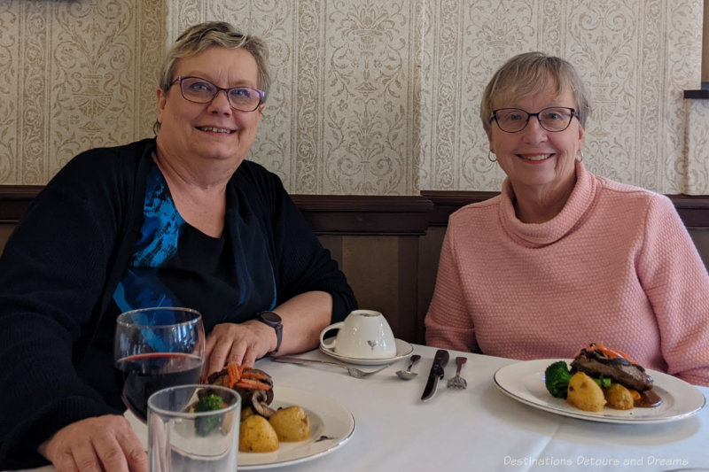 Two women at a restaurant table with plates of food in front of them