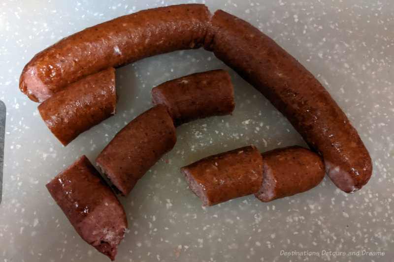 winnipeg-foods-farmers-sausage Cut pieces of a cooked sausage (farmer's sausage) one a white cutting board