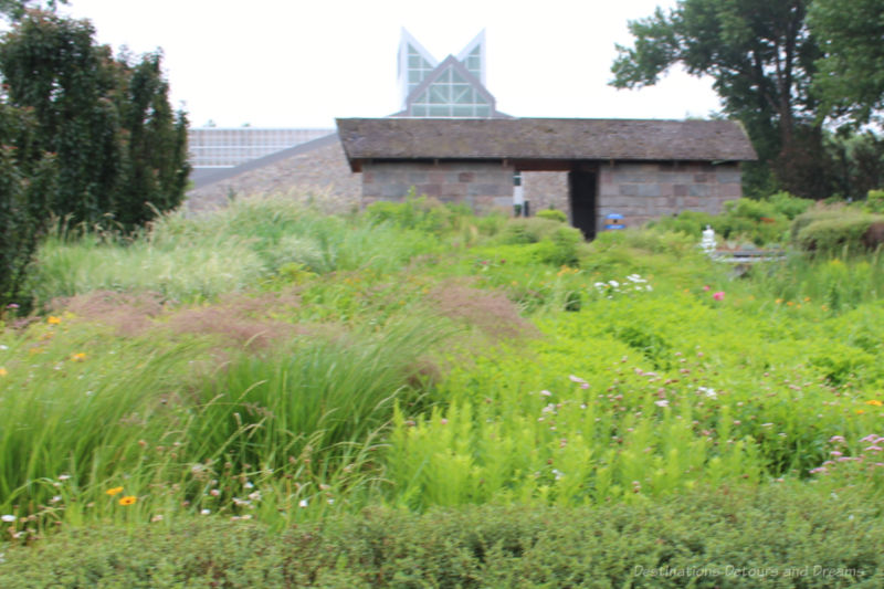Cottage garden area in foreground; building in background with glass roof and tower