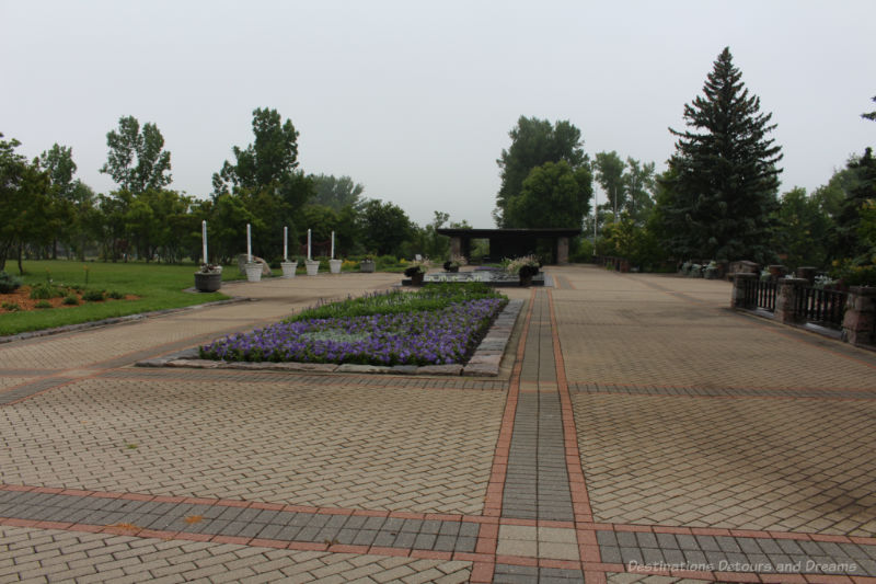 Large brick terraced area with flower beds and covered picnic shelter at one end