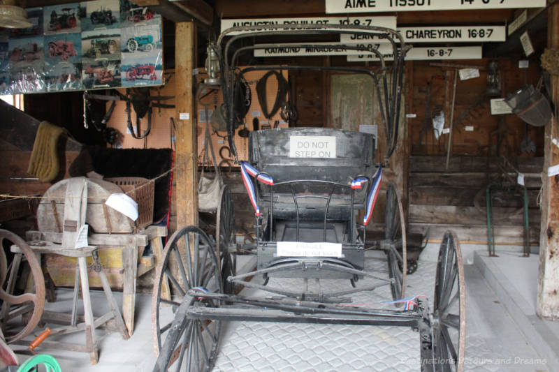 An old horse-drawn buggy and other other equipment inside a horse barn turned museum