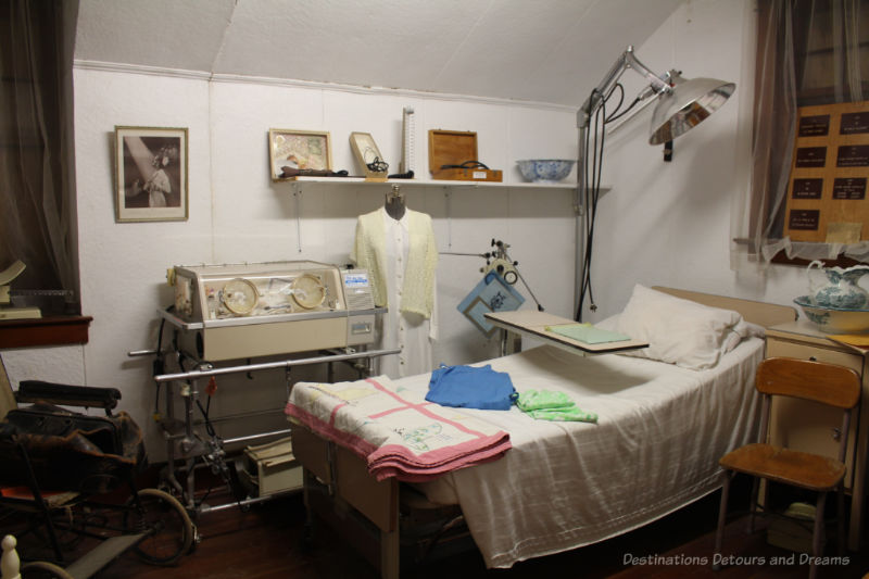 Recreation of an old hospital room in a museum contains bed, incubator, old wheelchair, and other vintage items