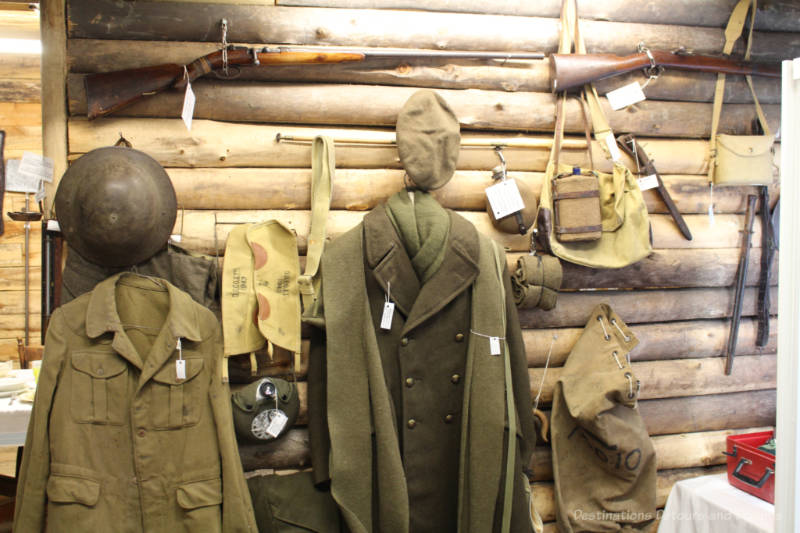 Display of vintage military wear and gear in front of a log wall