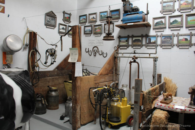 Museum displays of various milking machines and dairy equipment separated by half wooden walls like cattle barn separations