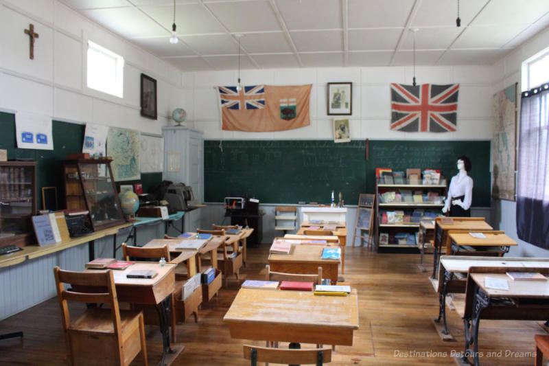 Old desks and books in museum recreation of one-room school with old flags on wall