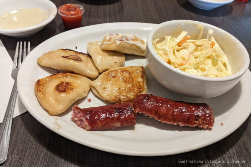 Winnipeg Food Perogies A plate of fried perogies, farmer sausage, and coleslaw