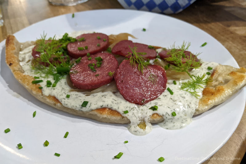 Winnipeg Food Gouda Potato Perogy Large smoked gouda potato blend perogy fills plate and is topped with dill cream, slices of kielbasa and fresh dill
