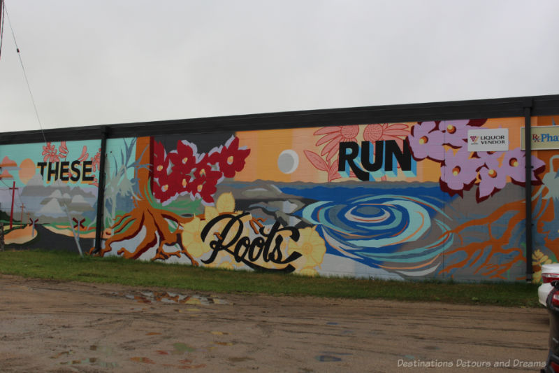 Boissevain Outdoor Art Gallery These Roots Outdoor mural shows abstract images of land, water, floral, with the words These Roots Run Deep