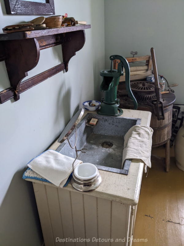Old laundry room in museum contains sink with pump and wringer-style washing machine
