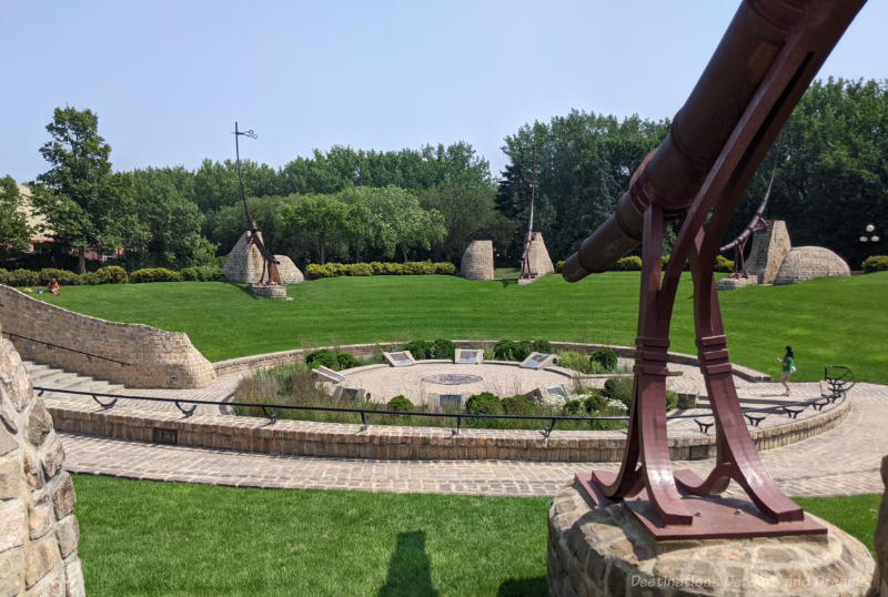 The Forks Turtle Tours Oodena Celebration Circle Concave section of grass with brick walkway in centre where there is a ceremonial fire pit and metal structures around the outside of the area providing a sundial