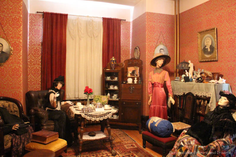 Daly House Museum Parlour Victorian-era parlour in a house museum features red and gold wallpaper, antique furniture and mannequins dressed in period clothing