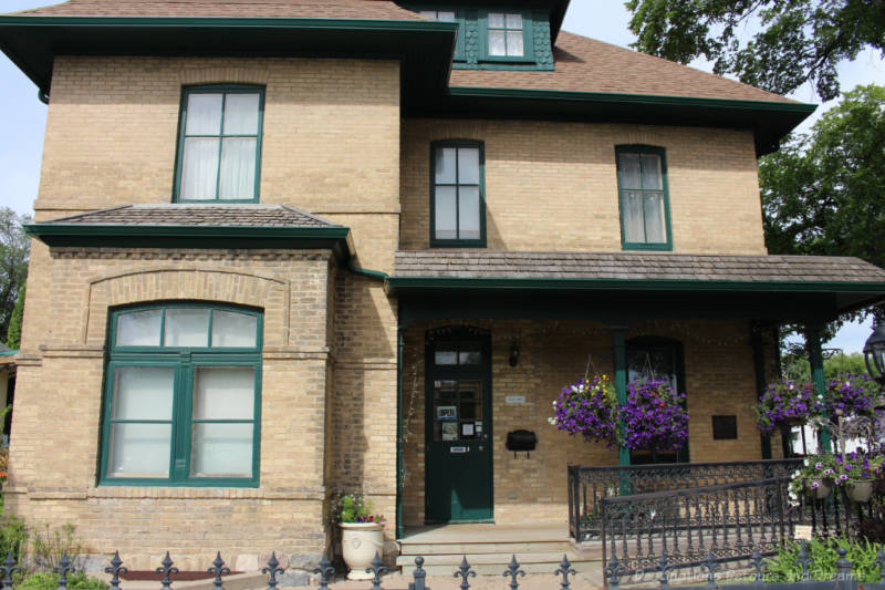 Daly House Museum Two-story light brown brick late nineteenth century house, now the Daly House Museum, with green window trim