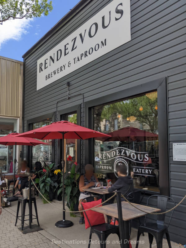 Rendezvous Patio Small sidewalk-adjacent patio with tables and red umbrellas in front of a taproom and eatery