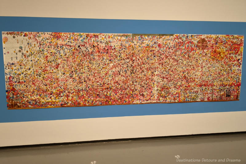 Staycation Red Giant A very large horizontal painting of many small faces grouped together to form a mass of colour with lots of red